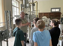 Istorinėje prof. Kazimiero Vasiliausko laboratorijoje inžinierius Romualdas Jakubauskas rodo bandymus ukrainiečiams vaikams, 2024 m. (Karinos Lazauskienės nuotr.)